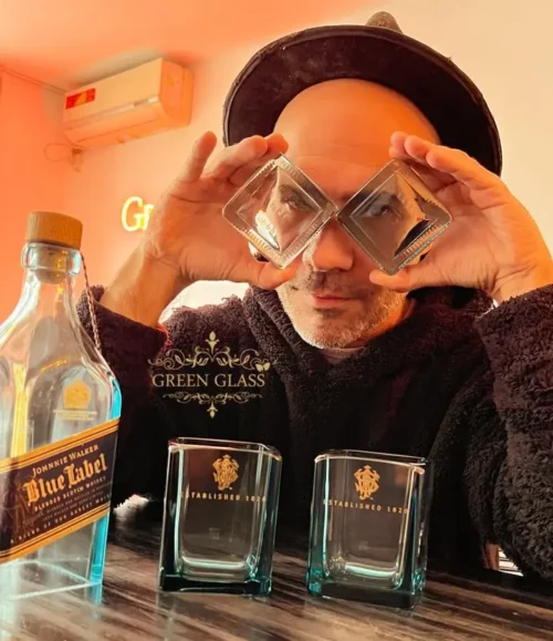 Lanchi artista y fundador de Green Glass retratado con apoyavasos de vidrio reciclado de botellas de Johnnie Walker Blue Label